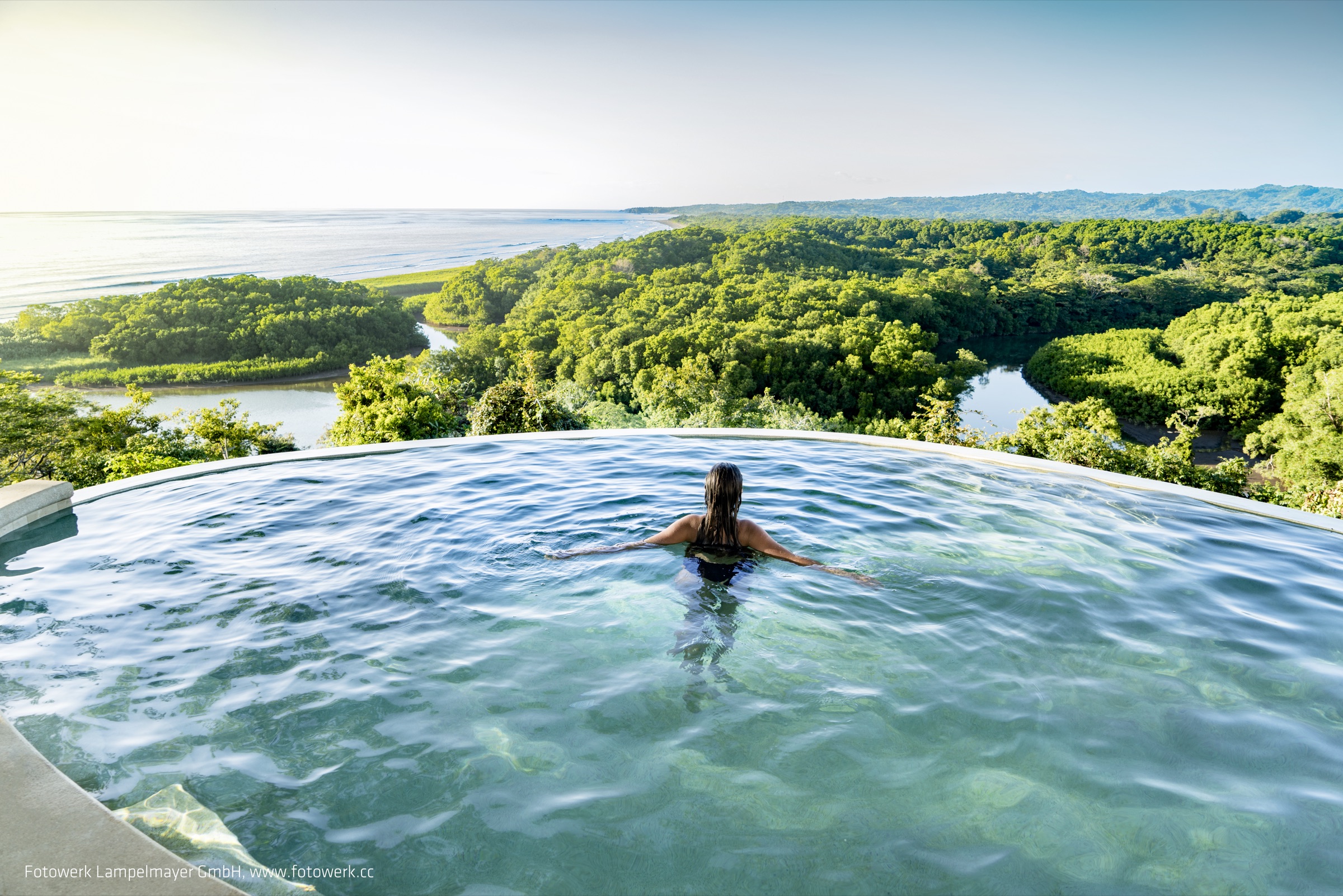 Guest enjoying the infinity pool overlooking forest, river and ocean at LaGarta Lodge